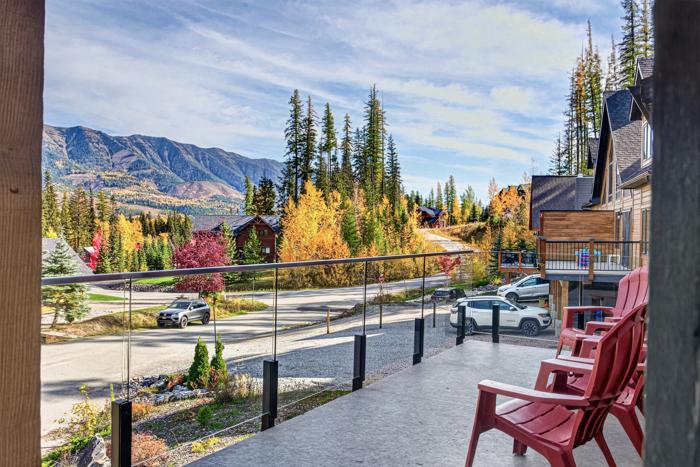 Covered deck with red Muskoka chairs and views of the Fernie valley