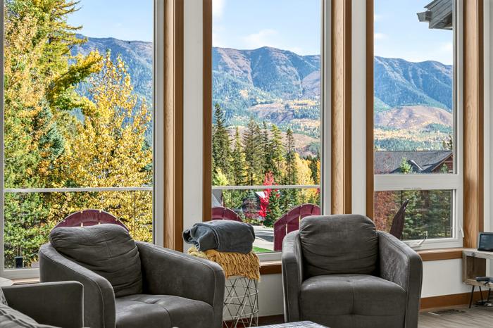 Living room chairs facing windows with a view of the mountains across the valley